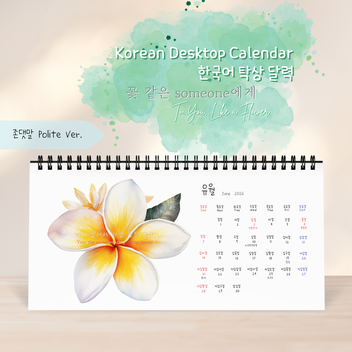 A Korean desktop calendar shown open on a light beige background with a soft green watercolor splash and decorative text above. The visible product is a spiral-bound monthly calendar page featuring a large white plumeria flower with yellow and peach tones on the left side and a June 2027 calendar grid on the right.